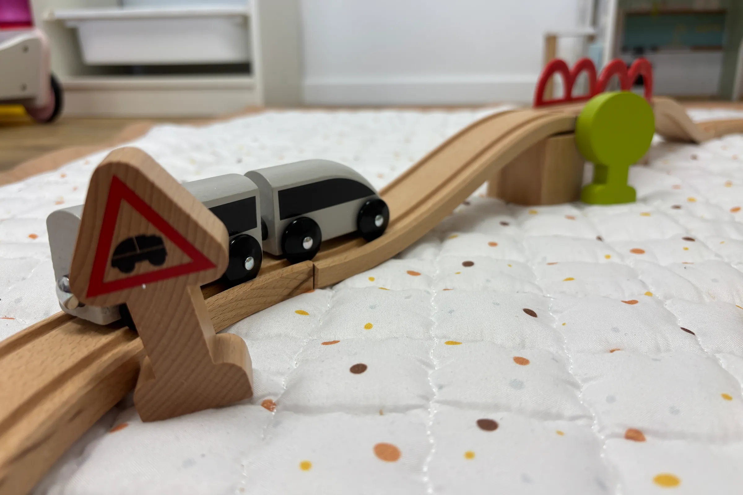 Een houten trein op een treinbaan over een speelkleed